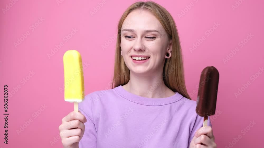 Happy young woman eating yellow ice cream on pink background. Concept of summer and sweet cold desserts. Happy young woman eating yellow ice cream on pink background. Concept of summer and sweet cold desserts.