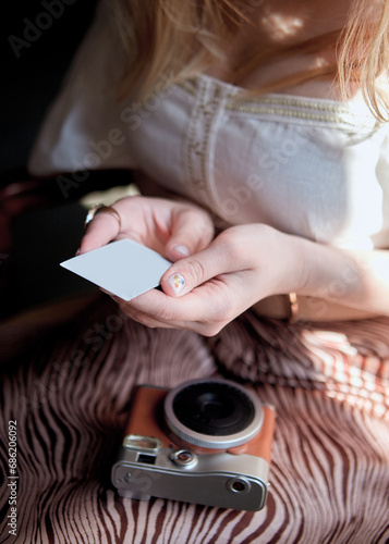 Close view of a girl holding a photo card from a retro camera mockup
