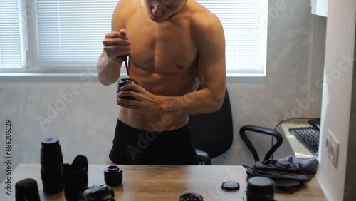 bare-chested man cleans and cares for optics and camera lenses. photo