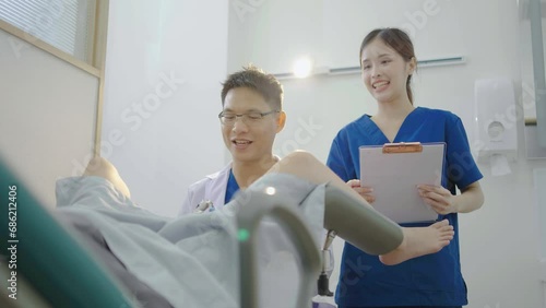 Male asian doctor doing internal examination on female patient at hospital room. They discussing about Illness with female patient at hospital, gynecological examination, conducting a pelvic exam photo