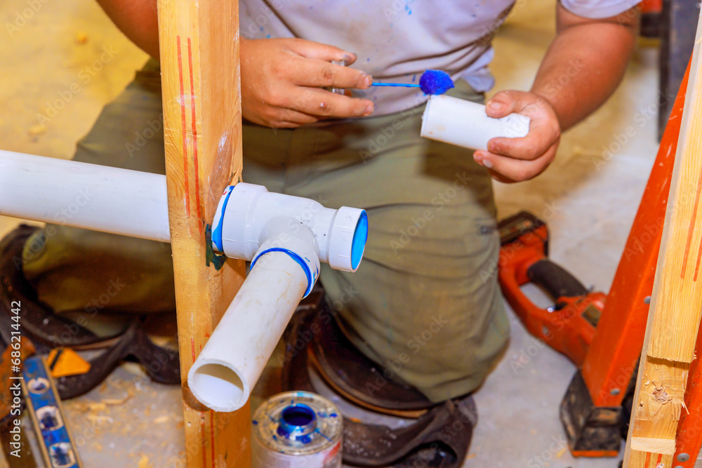 Plumber glues plastic drainage PVC pipes system new house construction