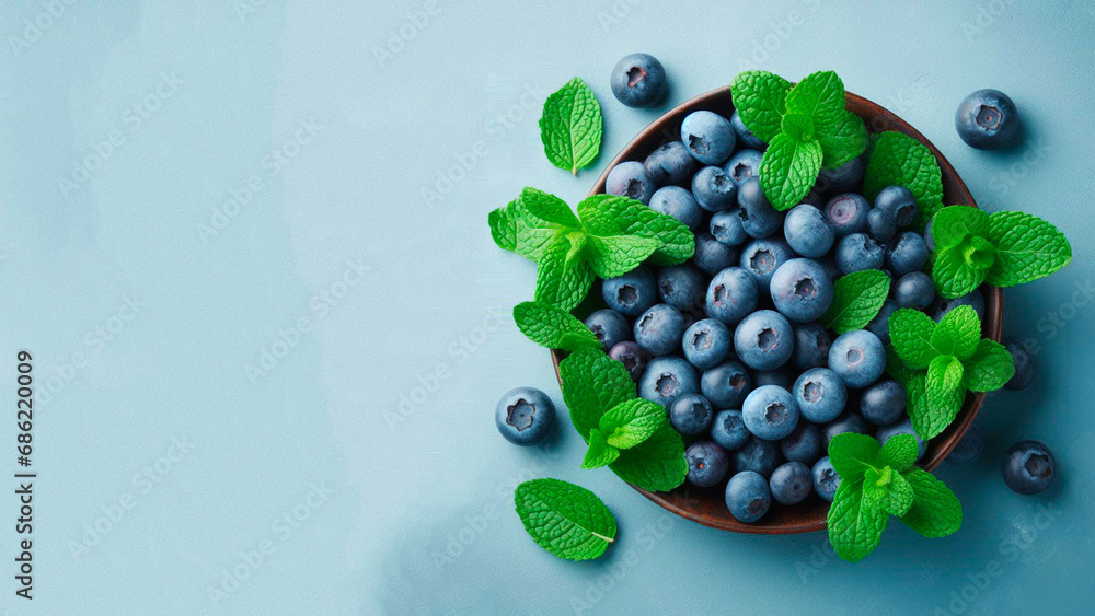 fresh ripe blueberries with mint leaves on a blue background fresh ripe blueberries with mint leaves on a blue background