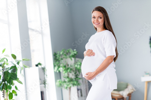 Profile side photo of positive sweet tender lovely mum pregnant girl touching her tummy enjoying sunny day at maternity hospital