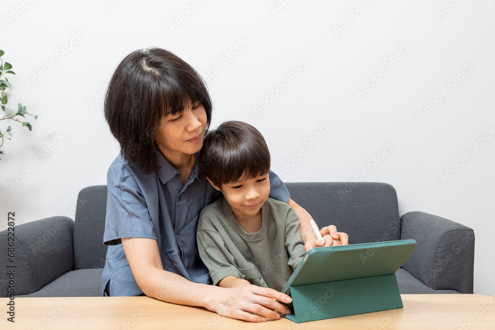 Asian woman mother use digital tablet with her son at home. Asian woman mother use digital tablet with her son at home.