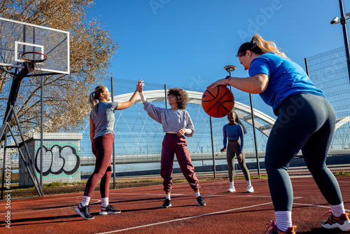 Diverse group of young woman having fun playing recreational basketball outdoors. © Zoran Zeremski