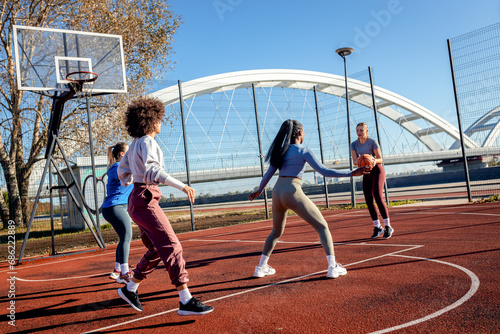Diverse group of young woman having fun playing recreational basketball outdoors. © Zoran Zeremski