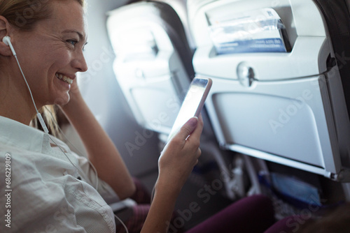 Smiling woman listening to music on airplane photo