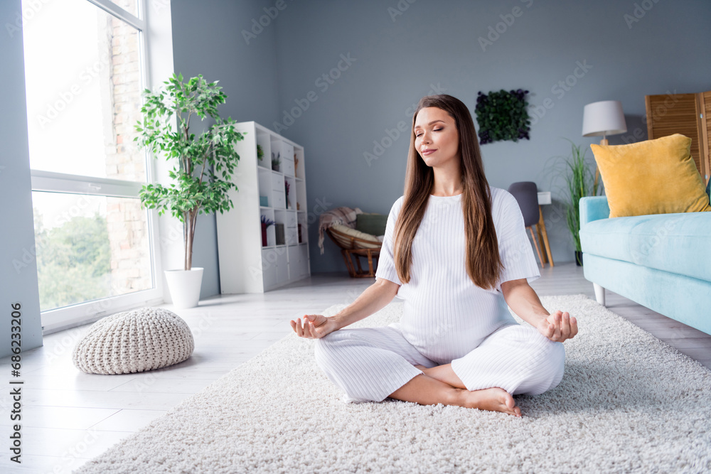 Photo of peaceful pretty cute adorable pregnant girl sitting on floor enjoying calm healthy pregnancy yoga indoors - obrazy, fototapety, plakaty 