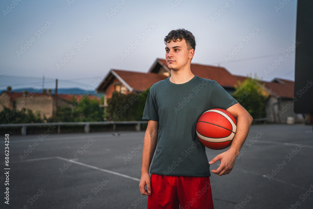 One caucasian teenager stand on basketball court with ball