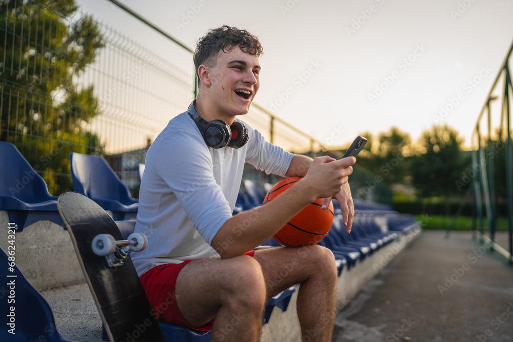 caucasian teen using mobile phone smartphone at a basketball court