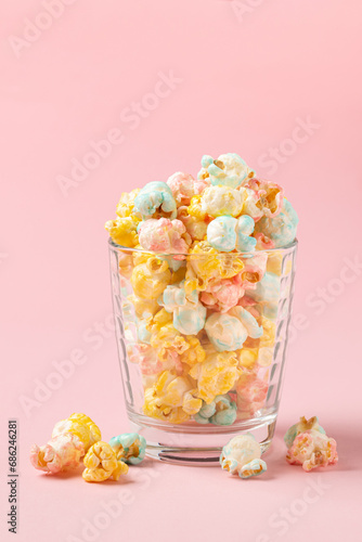 Multicolor sugary popcorn in glass  on a pink background with copy space