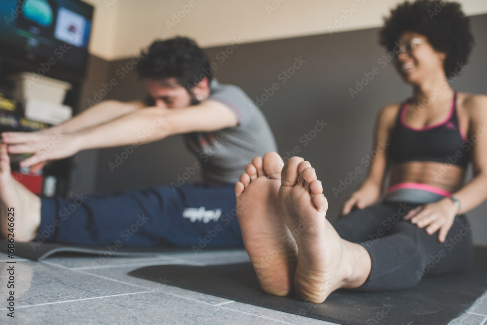 Multiethnic couple at home practicing sport doing fitness yoga Multiethnic couple at home practicing sport doing fitness yoga