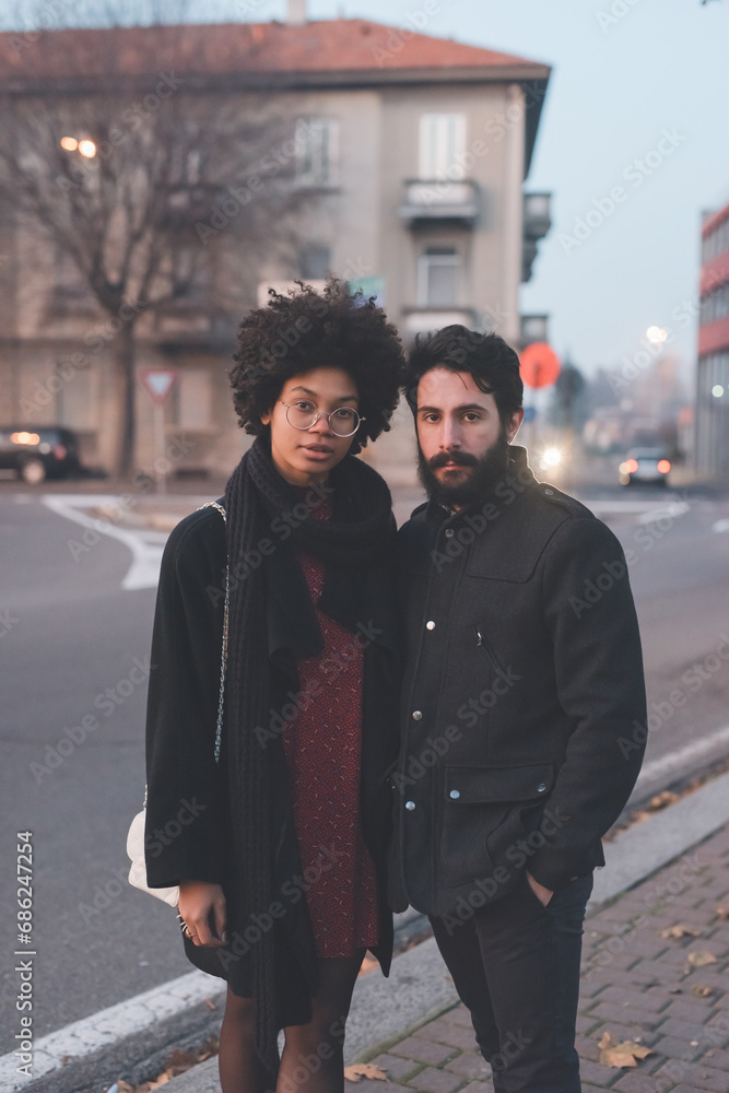 Young multiethnic couple posing outdoors city streets at sunset Young multiethnic couple posing outdoors city streets at sunset