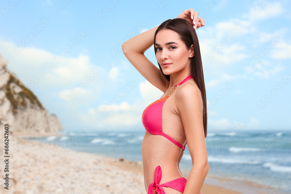 Beautiful woman in stylish pink bikini on sandy beach near sea, space for text