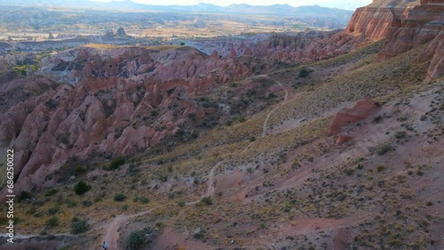 Experience the enchanting hues of the Red or Pink Valley near Goreme, Cappadocia, in this captivating aerial stock photo. The landscape, painted in warm tones, showcases the unique geological photo