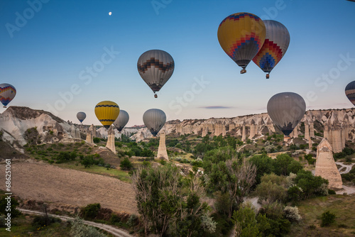 Hot air balloons flying over bizarre rock landscape in Cappadocia. Balloons fly early in the morning. Beautiful hot air balloons in the morning sky. Goreme. Turkey