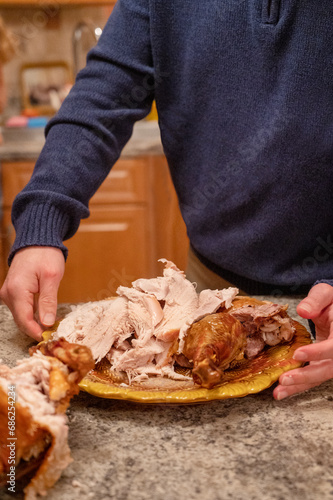 Thanksgiving dinner. Man staying in kitchen holding plate with roasted turkey. Getting ready for traditional dinner.