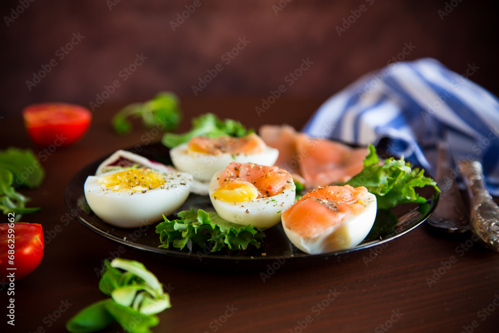 boiled eggs with salted red fish, herbs and seasonings in a plate .