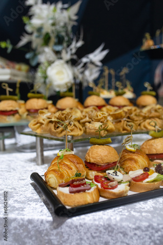 Croissants  burgers and various snacks on stands on the buffet table