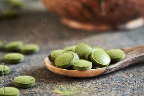 Green barley grass tablets on a spoon on a table