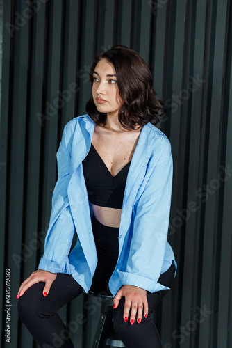 Beautiful young girl in black trousers and a blue jacket on a black background. Portrait of a beautiful young woman