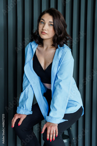 Beautiful young girl in black trousers and a blue jacket on a black background. Portrait of a beautiful young woman