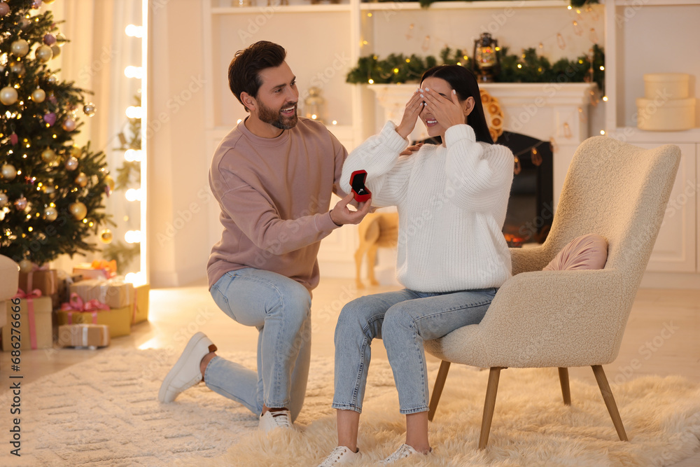 Obraz premium Man with engagement ring making proposal to his girlfriend at home on Christmas