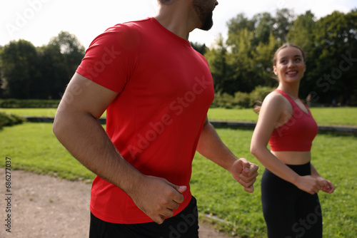 Healthy lifestyle. Couple running in park on sunny day, closeup