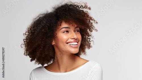 A charming and obnoxious woman makes flirty glances, gently smiles, tilts her head, alluringly giggles, grinning, toothy, delighted, enjoys a pleasant conversation with a white wall. photo