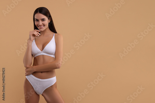 Young woman in stylish white bikini on beige background. Space for text