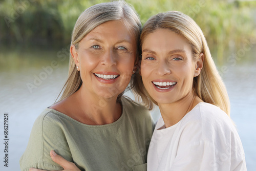 Family portrait of happy mother and daughter spending time together near pond photo