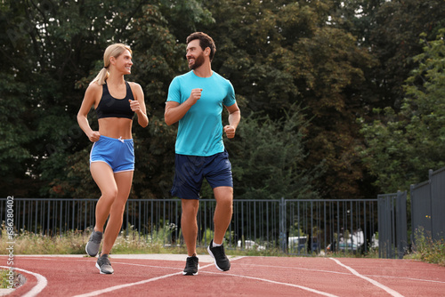 Healthy lifestyle. Happy sporty couple running at stadium, space for text