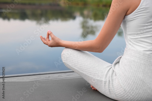 Woman practicing Padmasana on yoga mat outdoors, closeup, space for text. Lotus pose