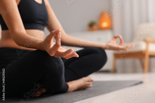 Woman practicing Padmasana on yoga mat at home  closeup and space for text. Lotus pose