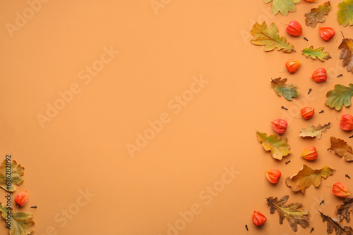 Dry autumn leaves and physalises on pale orange background, flat lay. Space for text