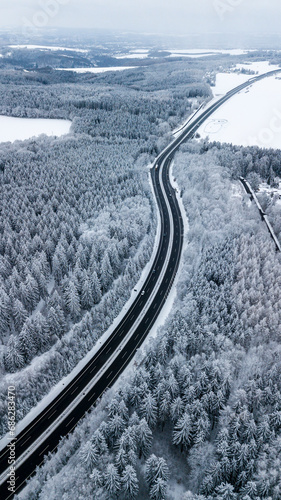 Landstraße durch verschneiten Wald im tiefsten Winter