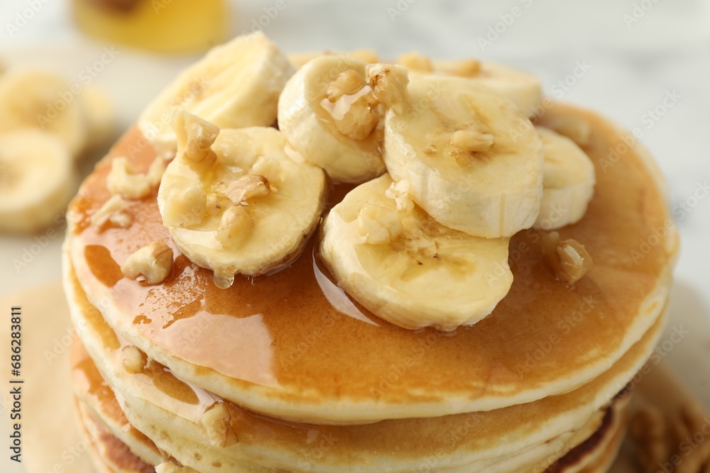 Delicious pancakes with bananas, walnuts and honey on table, closeup Delicious pancakes with bananas, walnuts and honey on table, closeup