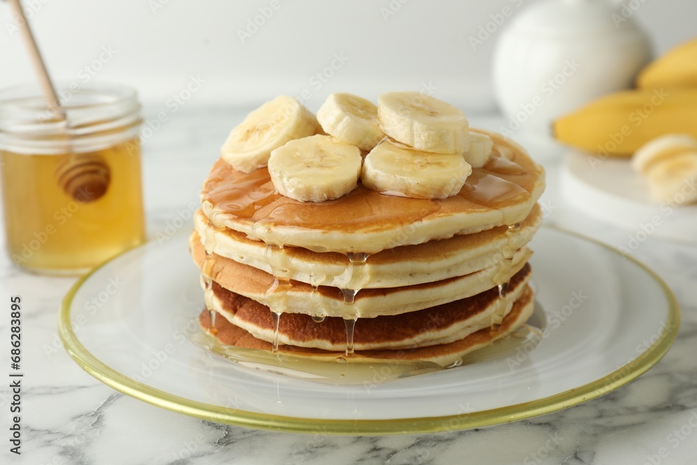 Delicious pancakes with bananas and honey on white marble table, closeup Delicious pancakes with bananas and honey on white marble table, closeup