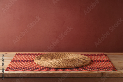 Empty wooden table with bamboo tablecloth and place mat over brown wall background.  Kitchen mock up for design and product display photo