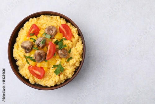 Tasty cornmeal with tomatoes, pepper and mushrooms in bowl on light table, top view. Space for text