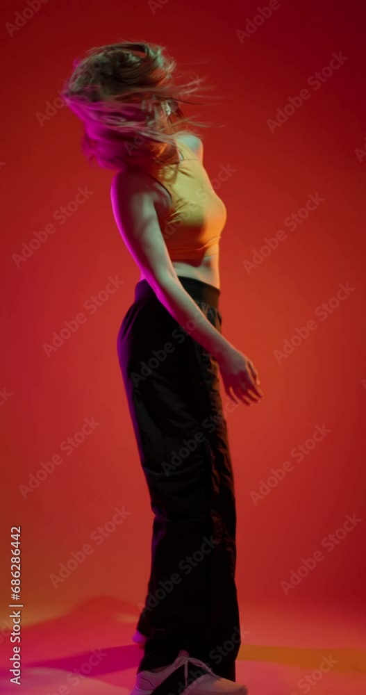 Girl dancing hip hop slow motion vertical video. Lady clubbing at disco party with colorful flashes of light on dark background. Girl dancing hip hop slow motion vertical video. Lady clubbing at disco party with colorful flashes of light on dark background.