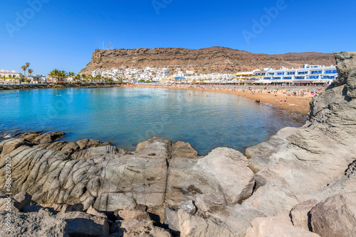 The sandy Playa Mogan beach and whitewashed fishing village at the seaside resort town of Puerto de Mogan, Spain, on the island of Gran Canaria, Canary Islands. photo