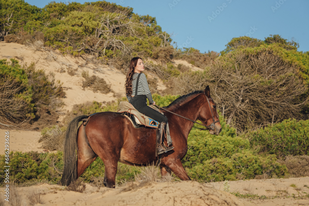 Smiling female horseback rider riding horse near sea Smiling female horseback rider riding horse near sea