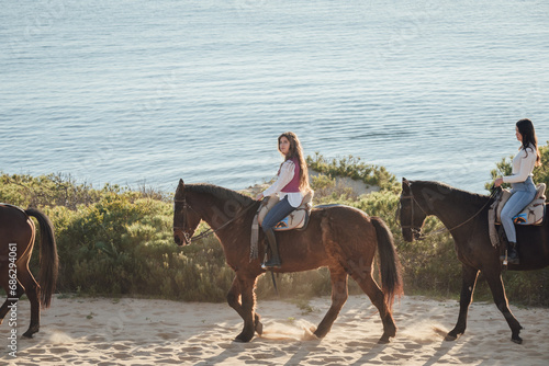 Young female equestrian riding brown horse along seashore