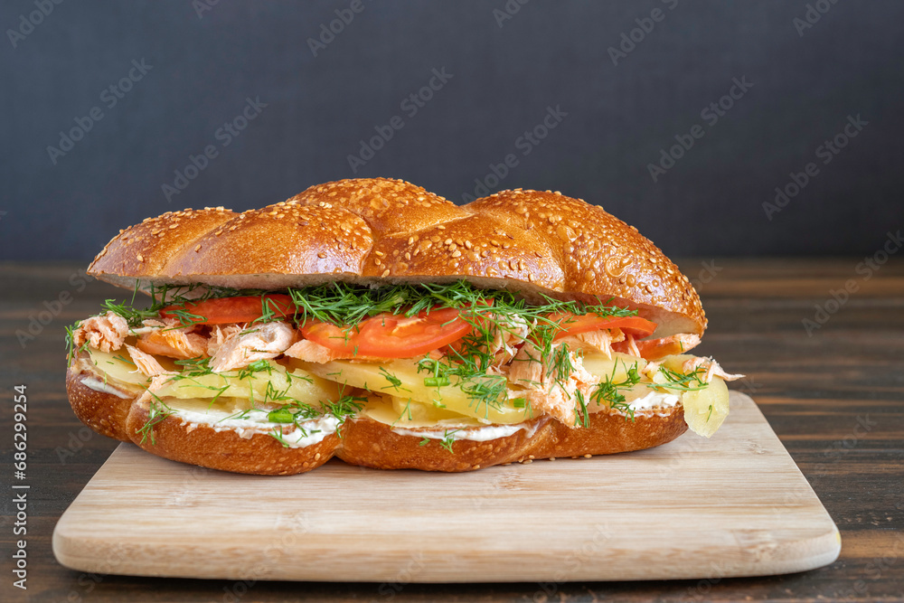 Challah Sandwich with grilled salmon, boiled potato, fresh tomatoes and fennel, cream cheese on wooden tray. Challah Sandwich with grilled salmon, boiled potato, fresh tomatoes and fennel, cream cheese on wooden tray.