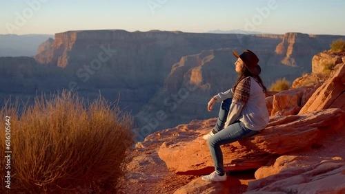 Young Native American woman wearing a cowboy hat standing at the amazing Grand Canyon - travel photography photo