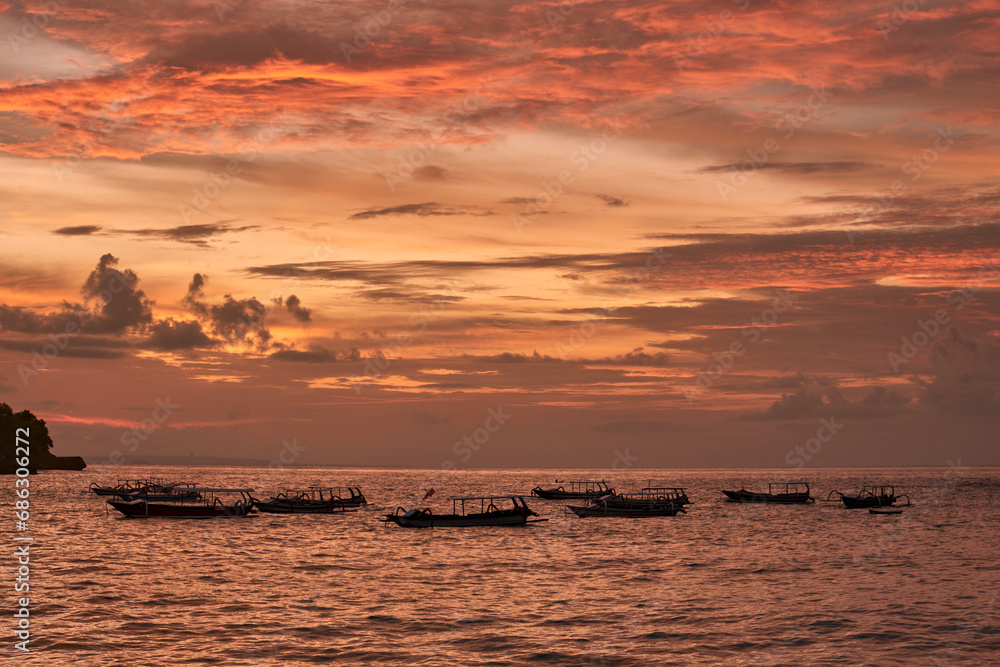 sunset over the sea with old boats, crystal bay in nusa penida