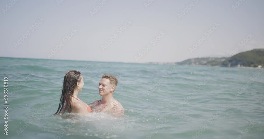 Couple having good time at sea. Boy throwing girl in the water. Summer fun concept. Recorded on cinema camera at 50fps Couple having good time at sea. Boy throwing girl in the water. Summer fun concept. Recorded on cinema camera at 50fps