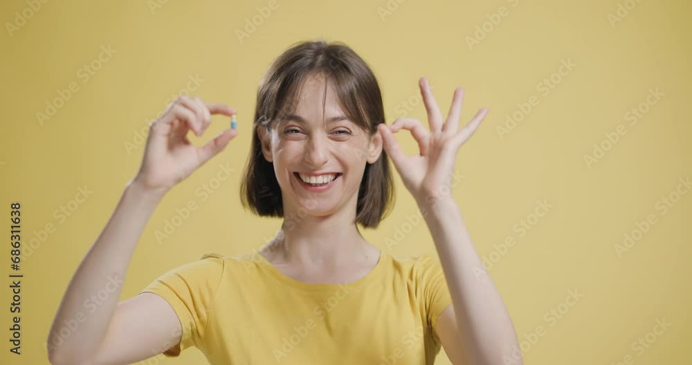 Girl in yellow shirt showing vertigo pill. Happy face like gesture with hand and delicious expression. Girl in yellow shirt showing vertigo pill. Happy face like gesture with hand and delicious expression.