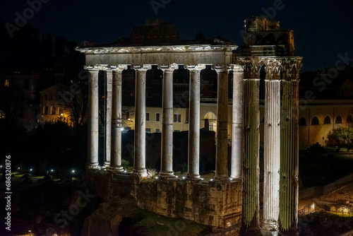 columns of the Temple of Saturn on the Palatine Hill illuminated at night with white light in the city of Rome.